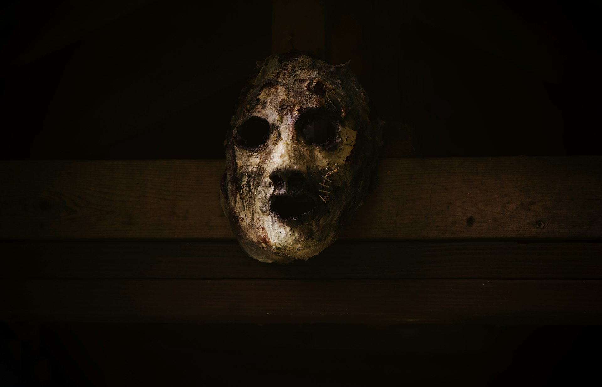 A creepy looking mask hanging on a wall