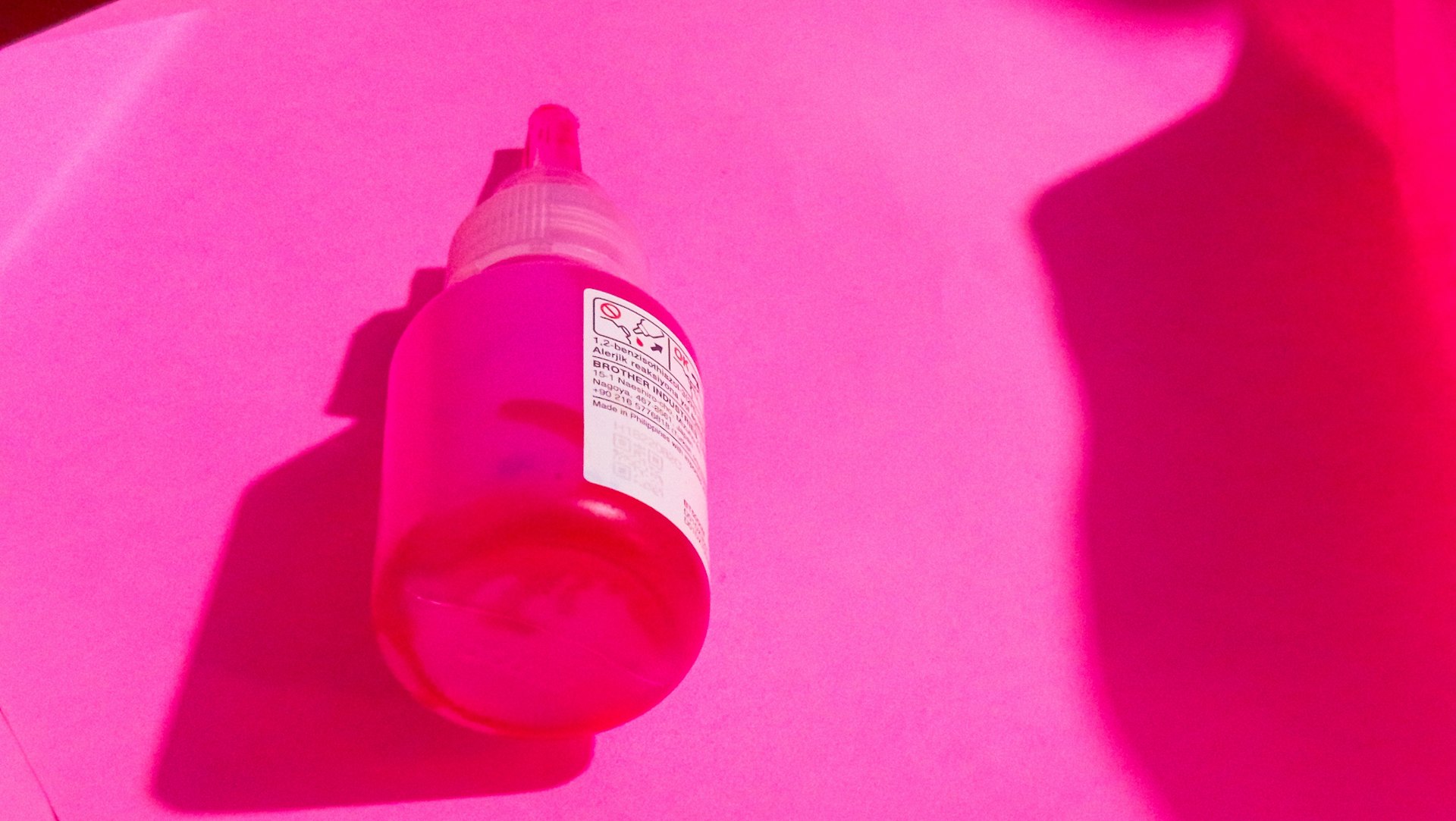 A pink bottle is shown in a pink light.